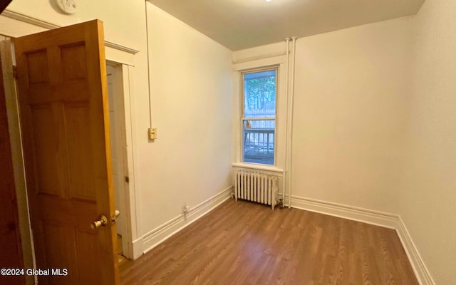 spare room with dark hardwood / wood-style flooring and radiator heating unit