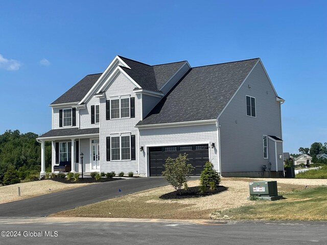 front of property featuring a garage, a porch, and central AC unit