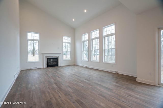 unfurnished living room with high vaulted ceiling, dark wood finished floors, visible vents, baseboards, and a glass covered fireplace