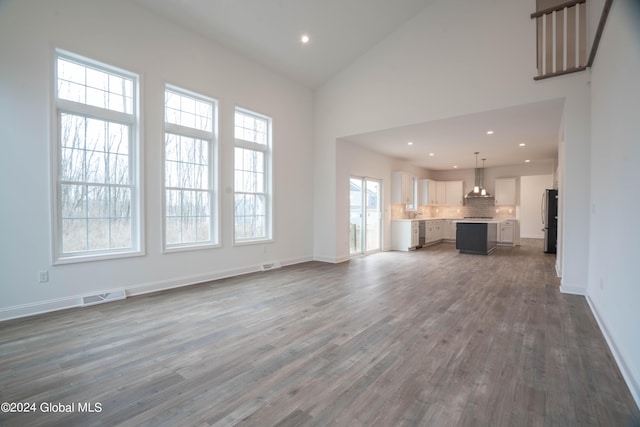 unfurnished living room with baseboards, visible vents, dark wood-type flooring, high vaulted ceiling, and recessed lighting