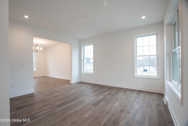 empty room featuring a chandelier, recessed lighting, dark wood finished floors, and baseboards