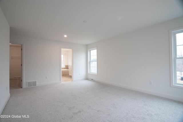 unfurnished bedroom with carpet flooring, a walk in closet, visible vents, and baseboards