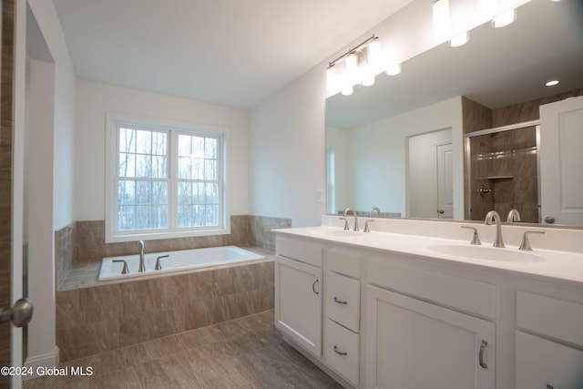 full bathroom with a garden tub, double vanity, a stall shower, and a sink