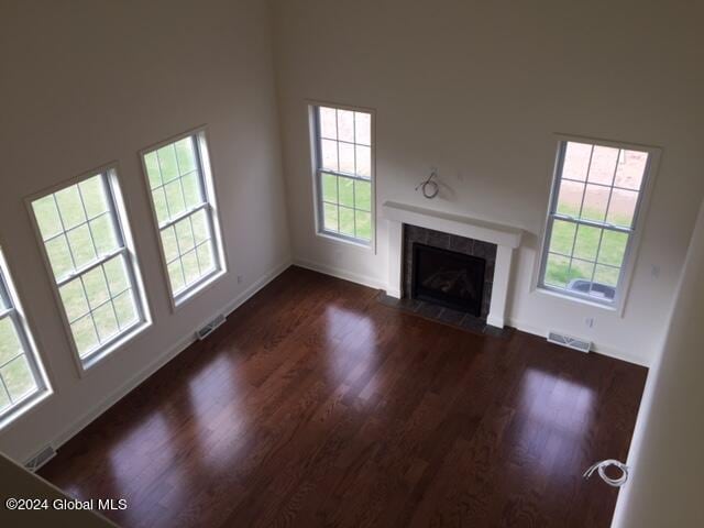 unfurnished living room with dark wood-type flooring, a tiled fireplace, and plenty of natural light