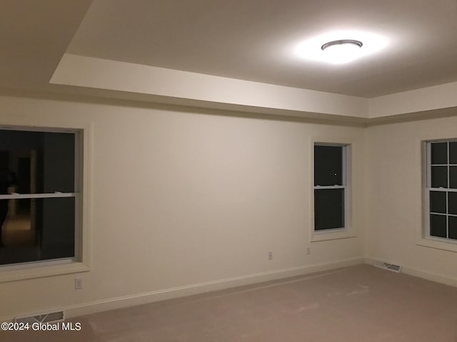 empty room with carpet, visible vents, and baseboards