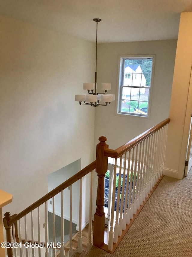 stairway with baseboards, a notable chandelier, and carpet flooring