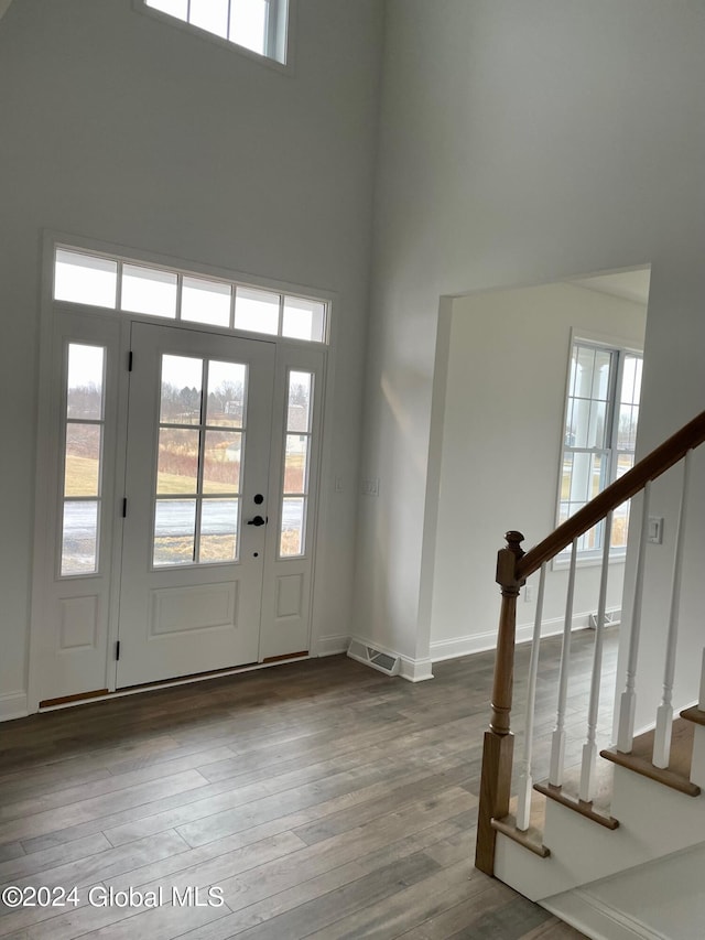 foyer entrance with visible vents, stairway, a towering ceiling, wood finished floors, and baseboards