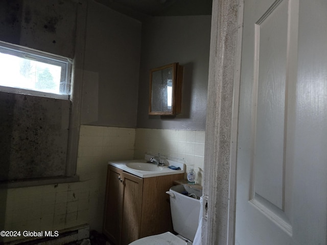 bathroom with tile walls, vanity, and toilet