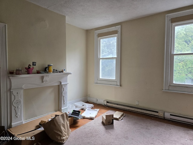 interior space with wood-type flooring, a textured ceiling, and baseboard heating