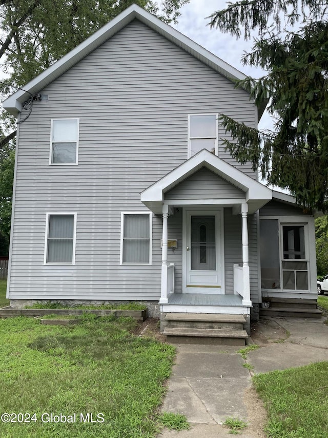 bungalow-style home featuring covered porch and a front lawn