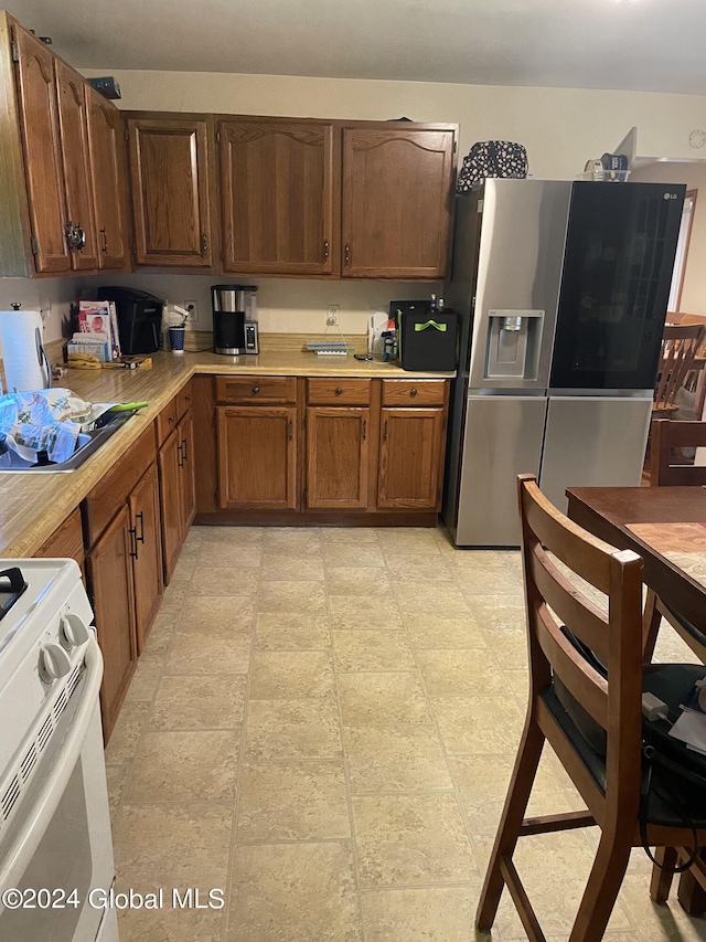 kitchen with light tile patterned flooring, white stove, and stainless steel fridge