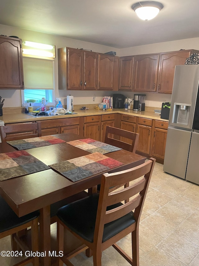 kitchen featuring sink, light tile patterned floors, and stainless steel fridge