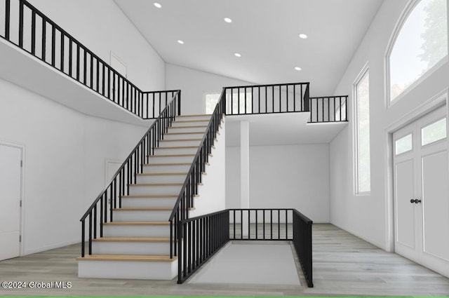 stairway with a towering ceiling and hardwood / wood-style flooring