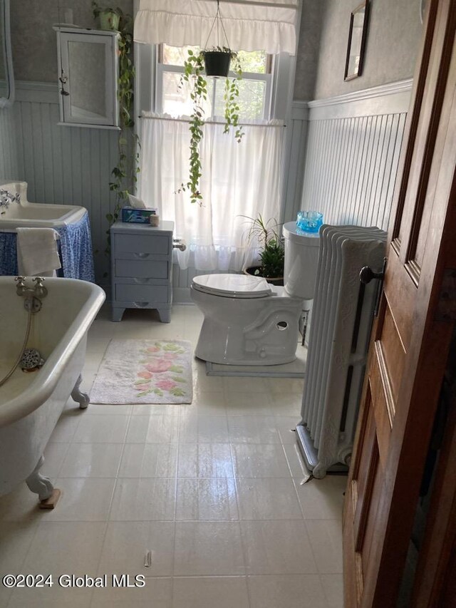 bathroom featuring a bathing tub, radiator heating unit, tile patterned flooring, and toilet