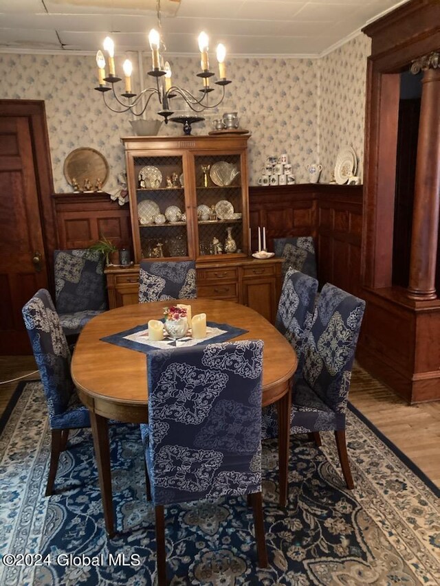 dining space with an inviting chandelier, ornamental molding, and hardwood / wood-style flooring