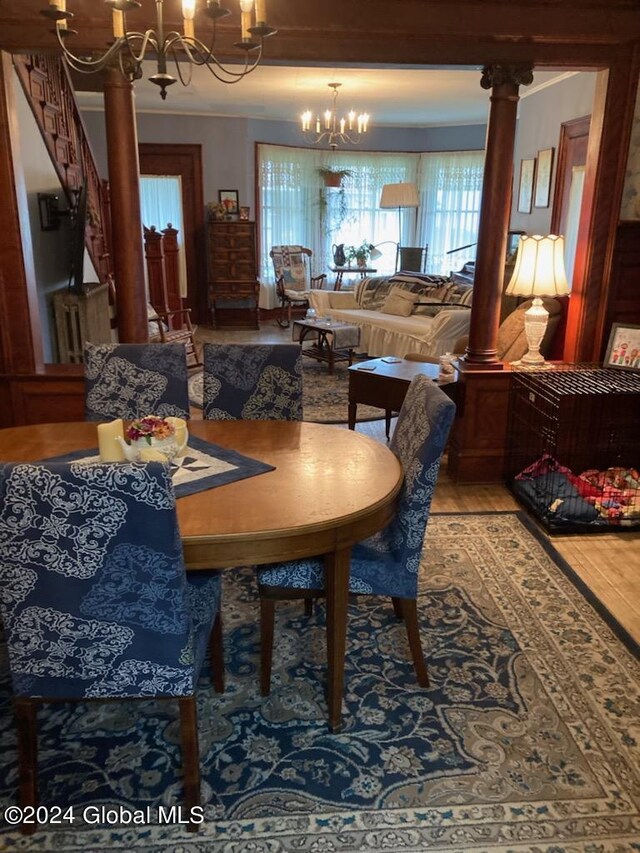 dining space featuring a notable chandelier, light hardwood / wood-style flooring, and ornate columns