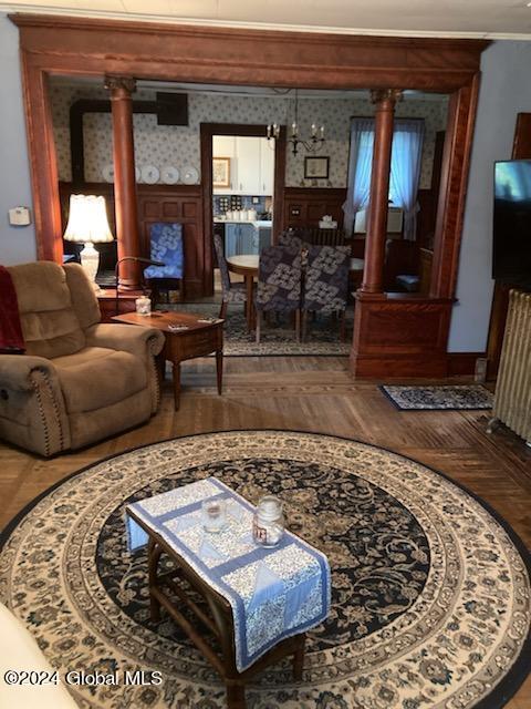 living room with decorative columns and hardwood / wood-style flooring