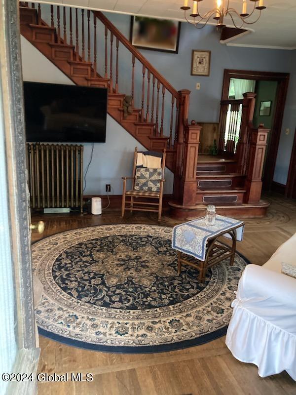 living room with a notable chandelier, radiator, and hardwood / wood-style flooring