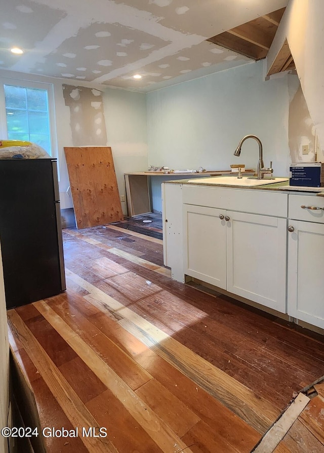 kitchen with stainless steel refrigerator, sink, dark wood-type flooring, and white cabinetry