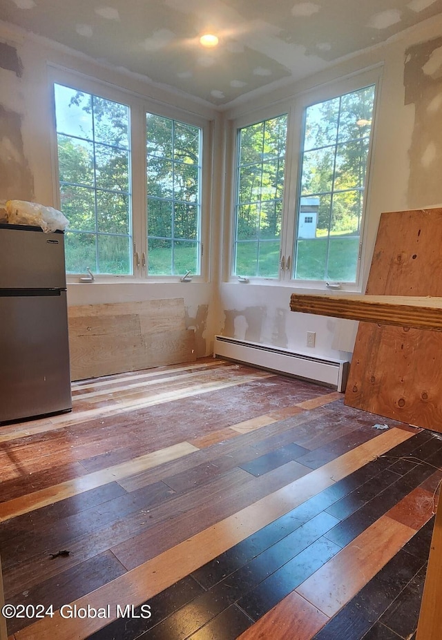 unfurnished room featuring baseboard heating, plenty of natural light, and dark hardwood / wood-style flooring