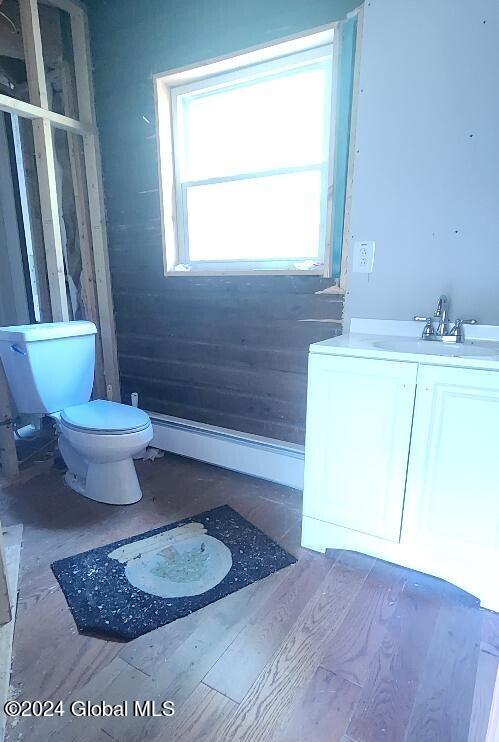 bathroom featuring vanity, toilet, a baseboard heating unit, and hardwood / wood-style flooring