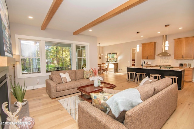 living room with beam ceiling, light hardwood / wood-style flooring, and sink