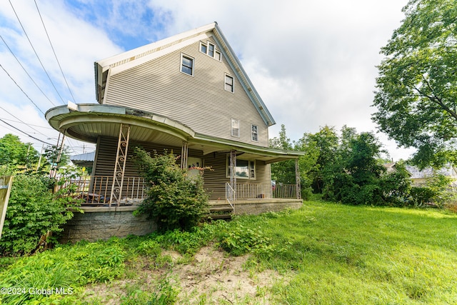 view of side of home featuring covered porch and a yard