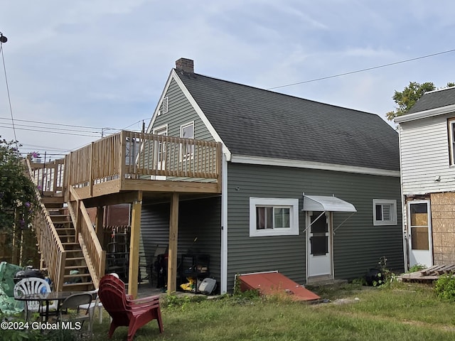 rear view of house featuring a wooden deck and a yard