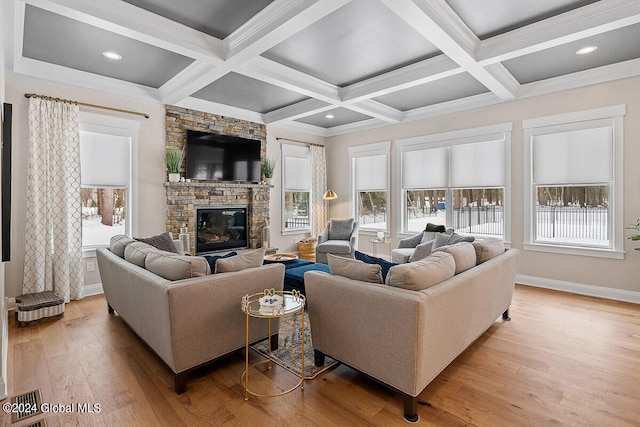 living room with beamed ceiling, a stone fireplace, light wood-type flooring, and coffered ceiling