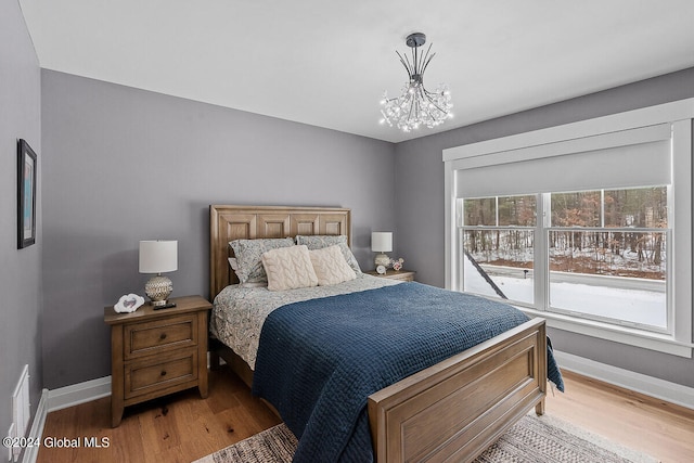 bedroom with an inviting chandelier and hardwood / wood-style floors