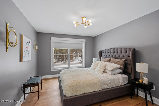 bedroom featuring wood-type flooring and an inviting chandelier