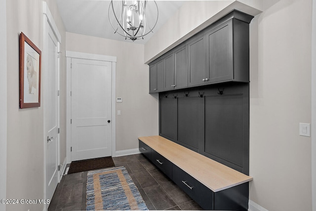 mudroom with an inviting chandelier and dark tile patterned floors