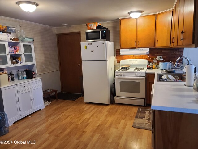 kitchen featuring light wood-type flooring, ornamental molding, white appliances, and decorative backsplash