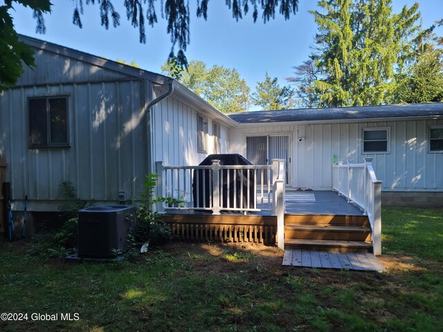 rear view of property featuring a wooden deck, a lawn, and central AC unit