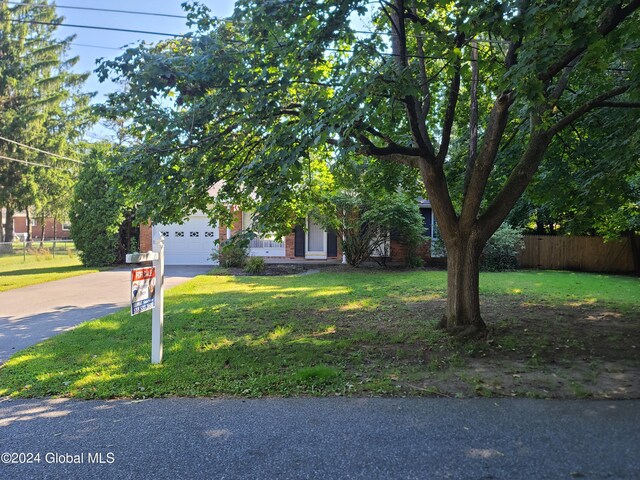 view of property hidden behind natural elements with a garage and a front yard