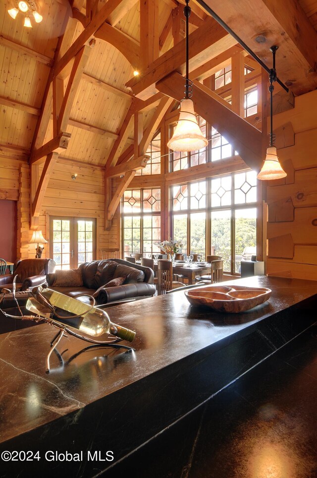 kitchen with beamed ceiling, high vaulted ceiling, decorative light fixtures, and wooden walls