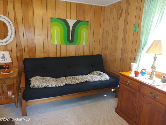 living area featuring light colored carpet and wooden walls