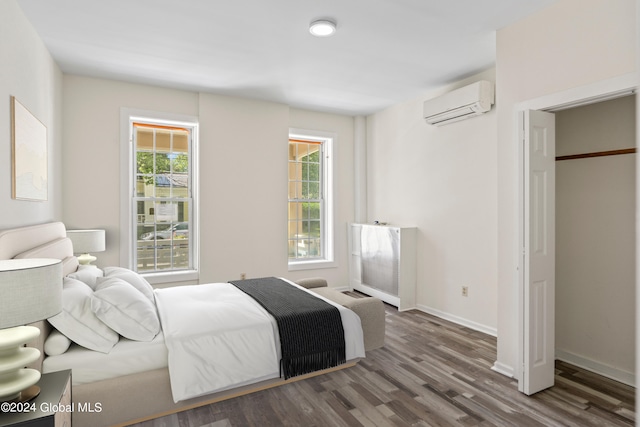 bedroom with an AC wall unit and dark wood-type flooring