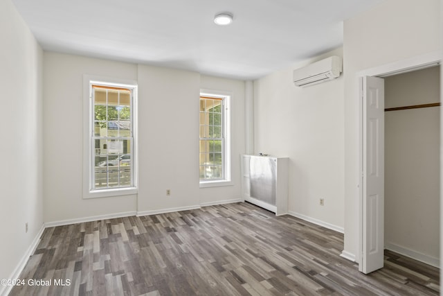 unfurnished bedroom with dark wood-type flooring and a wall mounted AC