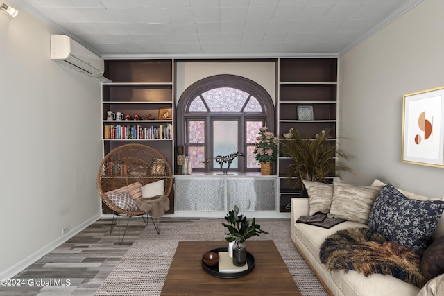 sitting room with hardwood / wood-style flooring, a wall mounted air conditioner, and built in shelves