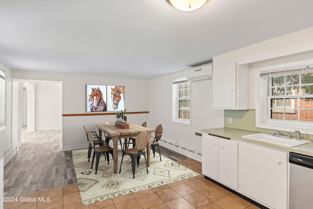 tiled dining area with sink, a wall mounted air conditioner, and a baseboard heating unit