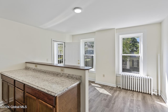 kitchen featuring light hardwood / wood-style flooring, radiator heating unit, and kitchen peninsula