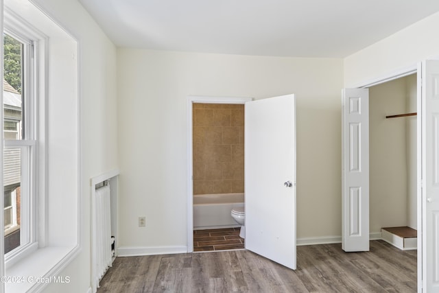 unfurnished bedroom with hardwood / wood-style floors and ensuite bathroom