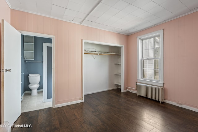 unfurnished bedroom with ornamental molding, radiator heating unit, dark hardwood / wood-style floors, and a closet