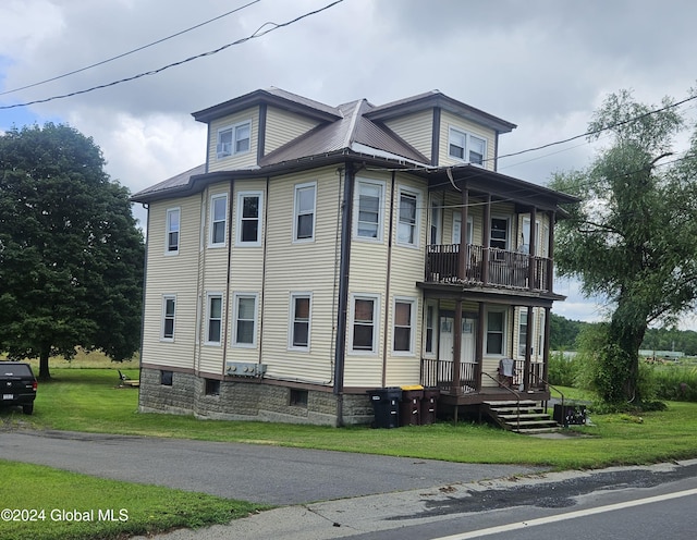 view of side of property featuring a balcony and a lawn