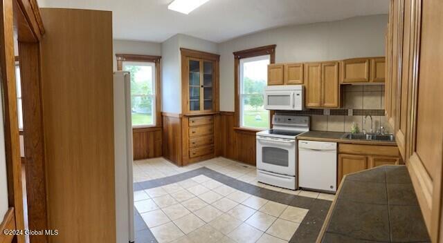 kitchen with light tile patterned flooring, a wealth of natural light, backsplash, and white appliances