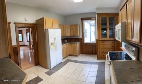 kitchen with white appliances, light tile patterned floors, and tile counters