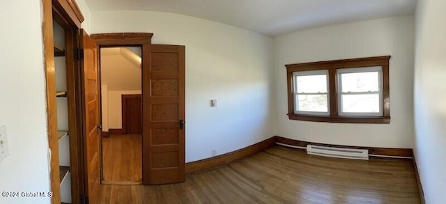 spare room featuring a baseboard heating unit and hardwood / wood-style floors