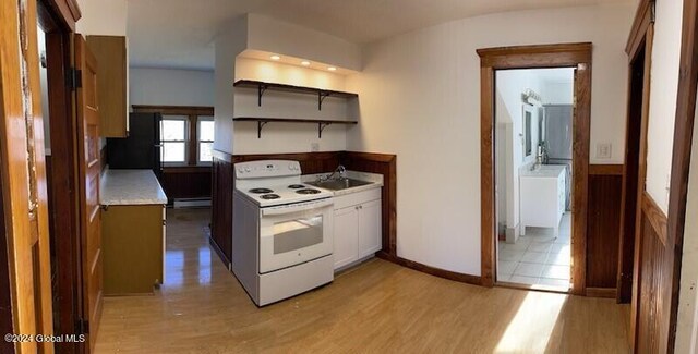 kitchen with light hardwood / wood-style floors, white cabinetry, a baseboard heating unit, sink, and white range with electric stovetop