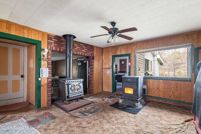 interior space with dark colored carpet, a wood stove, and wood walls